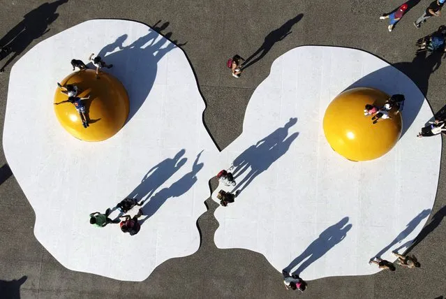 Children play on the “Art Eggcident”, urban art installation by the Dutch artist Henk Hofstra during the “Hecho en Casa”, festival at the Parque de la Familia, in Santiago, Chile, Thursday, October 28, 2021. (Photo by Esteban Felix/AP Photo)