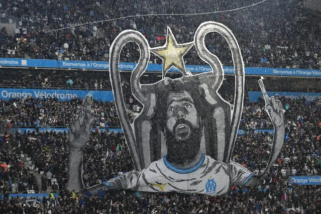 A tifo depicting French-Algerian comedian Redouane Bougheraba and the Champions League trophy is displayed by Marseille supporters prior to the French L1 football match between Olympique Marseille (OM) and Paris Saint-Germain (PSG) at Stade Velodrome in Marseille, southeastern France, on March 31, 2024. (Photo by Nicolas Tucat/AFP Photo)