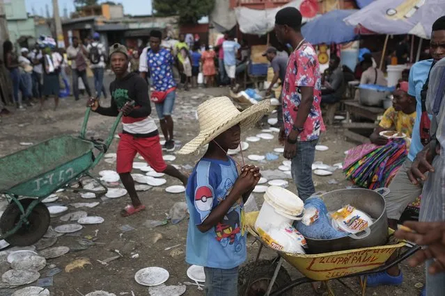 A youth waits for his cooked meal bought at a public market in Port-au-Prince, Haiti, Monday, November 15, 2021. (Photo by Matias Delacroix/AP Photo)