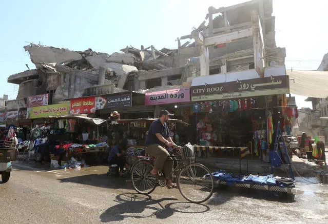 A man rides a bike passing by the shops along the street in Raqqa, Syria, May 29, 2019. (Photo by Aboud Hamam/Reuters)