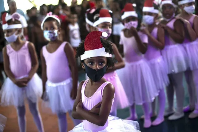 A young ballet dancer waits to perform at a Christmas celebration in the Vila OlÃ­mpica at the Vila Kennedy favela, in Rio de Janeiro, Brazil, Saturday, December 11, 2021. (Photo by Bruna Prado/AP Photo)