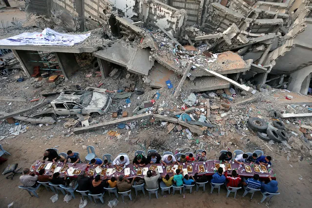 Palestinians break their fast by eating the Iftar meals during the holy month of Ramadan, near the rubble of a building recently destroyed by Israeli air strikes, in Gaza City on May 18, 2019. (Photo by Ibraheem Abu Mustafa/Reuters)