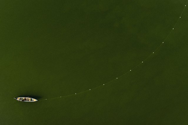 This aerial view shows a fisherman sitting in his boat after casting a net in the Shatt al-Arab river, formed at the confluence of the Tigris and Euphrates rivers, in Iraq's southern city of Basra on April 15, 2024. (Photo by Hussein Faleh/AFP Photo)