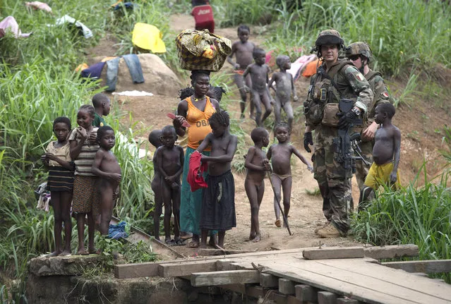 French soldiers of the 13th Alpine Hunters Battalion (13th BCA) stand beside children as they patrol near the northwestern city of Boda on April 7, 2014. Thousands of people have been killed in a wave of sectarian violence across the Central African Republic that has lasted for more than a year, despite the presence of African Union and French peacekeeping troops. (Photo by Miguel Medina/AFP Photo)