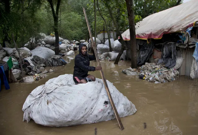 Indian man crosses a flooded neighborhood on a makeshift raft in Srinagar, Indian controlled Kashmir, Thursday, June 25, 2015. Authorities advised people living in low-lying areas to shift to safer places Thursday as rain-swollen rivers swamped several parts of the disputed Himalayan region. (Photo by Dar Yasin/AP Photo)