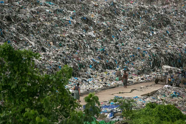 People walk past a garbage dump on the outskirts of Yangon, Myanmar on June 5, 2019. (Photo by Sai Aung Main/AFP Photo)