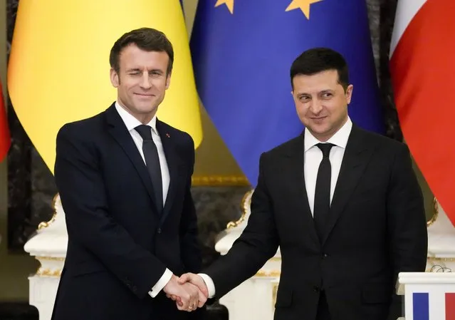 French President Emmanuel Macron, left, winks as he shakes hands with Ukrainian President Volodymyr Zelenskyy after a joint news conference following their talks in Kyiv, Ukraine, Tuesday, February 8, 2022. Diplomatic efforts to defuse the tensions around Ukraine continued on Tuesday with French President Emmanuel Macron arriving in Kyiv the day after hours of talks with the Russian leader in Moscow yielded no apparent breakthroughs. (Photo by Efrem Lukatsky/AP Photo)
