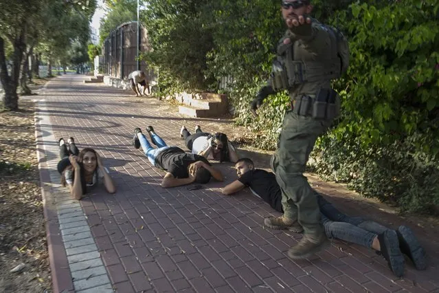 Israelis take cover as a siren sounds a warning of incoming rockets fired from the Gaza Strip, in Ashkelon, southern Israel, Sunday, May 16, 2021. (Photo by Heidi Levine/AP Photo)
