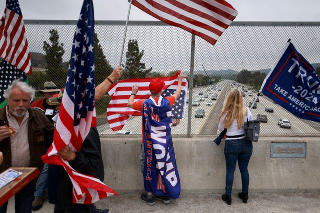 People stand with flags as supporters of former U.S. President Donald Trump rally in his support during what they call a "MAGA Cruise to stand up for Trump", in Thousand Oaks, California on June 1, 2024. (Photo by David Swanson/Reuters)