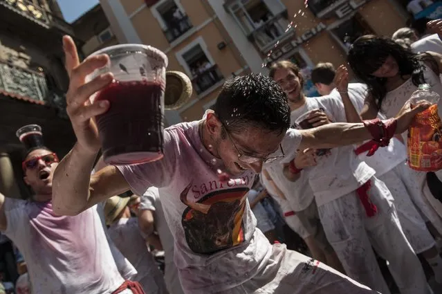 A reveler celebrates during the launch of the “Chupinazo” rocket, to celebrate the official opening of the 2015 San Fermin Fiestas, in Pamplona, northern Spain, Monday, July 6, 2015. Revelers from around the world kick off the festival with a messy party in the Pamplona town square, one day before the first of eight days of the running of the bulls. (Photo by Alvaro Barrientos/AP Photo)