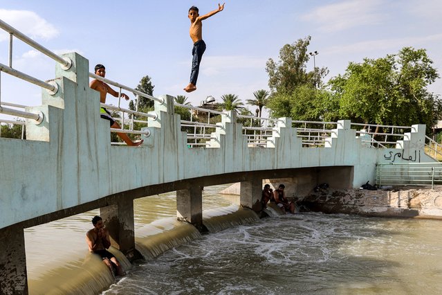 A boy jumps to dive into a canal of the Tigris river in Baghdad amid a soaring heatwave on June 18, 2024 on the third day of the Muslim holiday of Eid al-Adha. (Photo by Ahmad Al-Rubaye/AFP Photo)