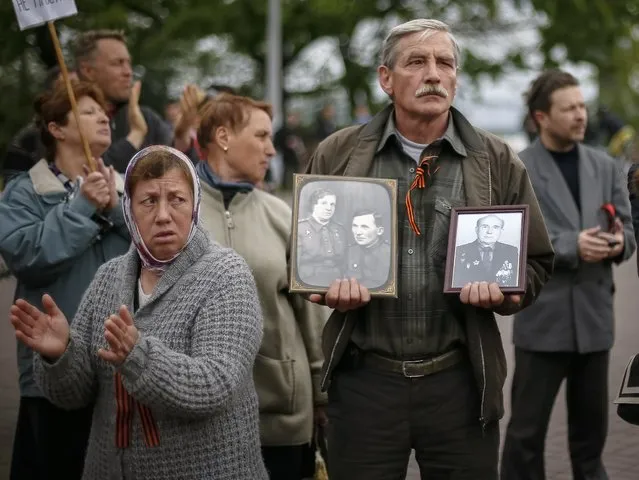 A man holds photographs of Soviet service personnel during celebrations to mark Victory Day in the Black Sea port of Odessa May 9, 2014. (Photo by Gleb Garanich/Reuters)