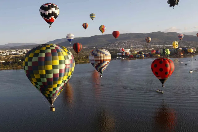 Hot-air balloons fly above the Papalote dam during the International Hot Air Balloon Festival in Leon, Mexico, Friday, November 12, 2021. (Photo by Mario Armas/AP Photo)