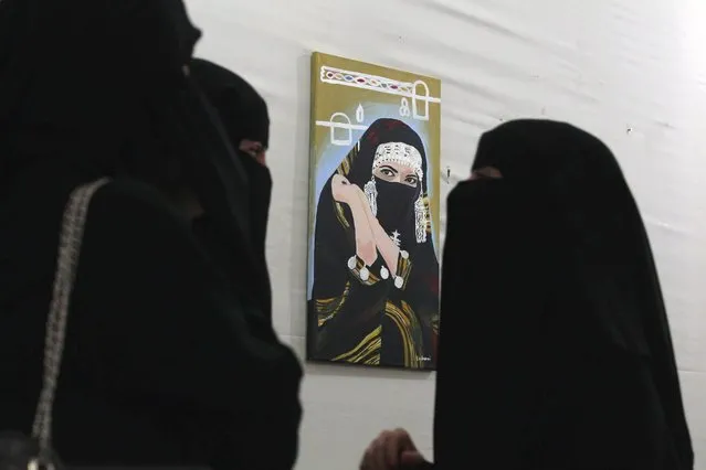 Visitors stand in front of an artwork by Yemeni female artist Amhani al-Warith during an art exhibition protesting against a Saudi-led year-long military campaign in Yemen, Sana'a, Yemen, 25 May 2016. An artwork exhibition was held in Sana'a to protest against Saudi-led military operations against Yemen and to urge all warring factions to prevent Yemen's backsliding into civil war. (Photo by Yahya Arhab/EPA)