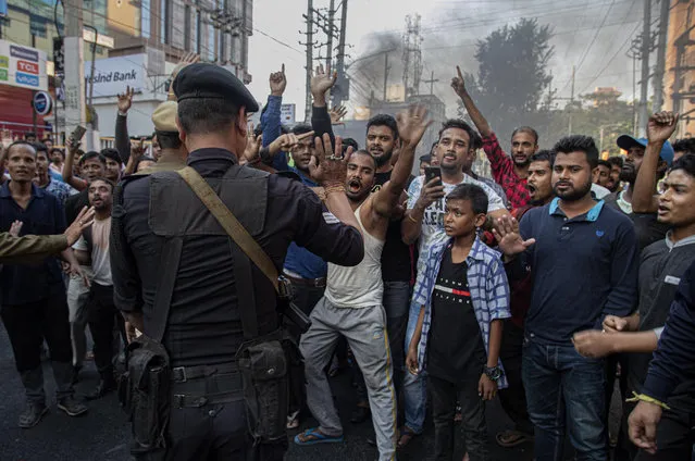 An Indian commando tries to stop as protesters block traffic during a shutdown protest against the Citizenship Amendment Bill (CAB) in Gauhati, India, Tuesday, December 10, 2019. Opponents of legislation that would grant Indian citizenship to non-Muslim illegal migrants from Pakistan, Bangladesh and Afghanistan have enforced an 11-hour shutdown across India's northeastern region. (Photo by Anupam Nath/AP Photo)