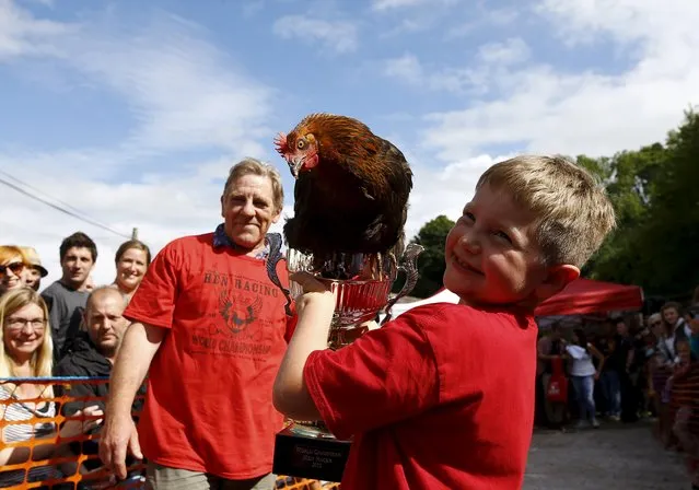 Jack Allsop-Smith (R) aged 7 celebrates with his hen “Cooked it” after winning the World Hen Racing Championships in Bonsall, Britain, August 1, 2015. (Photo by Darren Staples/Reuters)