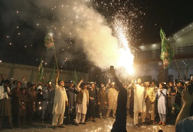 Supporters of newly-elected Pakistani Prime Minister Shahbaz Sharif celebrate outside their party office, in Peshawar, Pakistan, Monday, April 11, 2022. Pakistan's parliament elected opposition lawmaker Sharif as the new prime minister Monday, following a week of political turmoil that led to the weekend ouster of Premier Imran Khan. (Photo by Muhammad Sajjad/AP Photo)