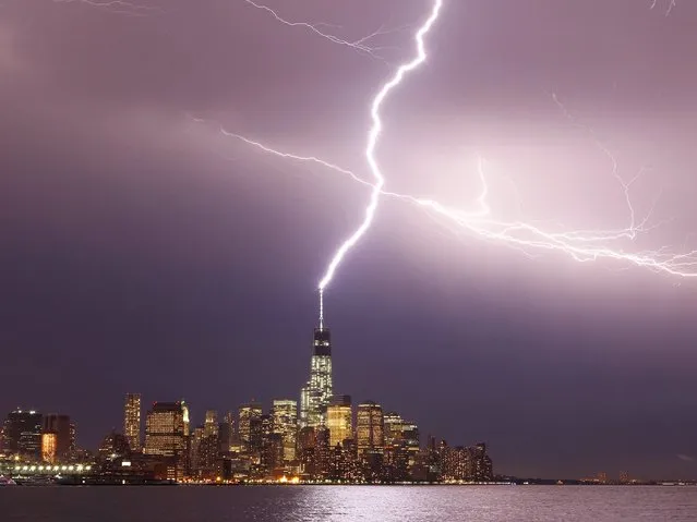 Lightning hits One World Trade Center in Lower Manhattan during an early evening storm in New York, July 2, 2014. (Photo by Gary Hershorn/Corbis Images)