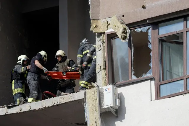 Rescue workers evacuate a person from a residential building damaged by a Russian missile strike, as Russia's attack on Ukraine continues, in Kyiv, Ukraine on June 26, 2022. (Photo by Valentyn Ogirenko/Reuters)