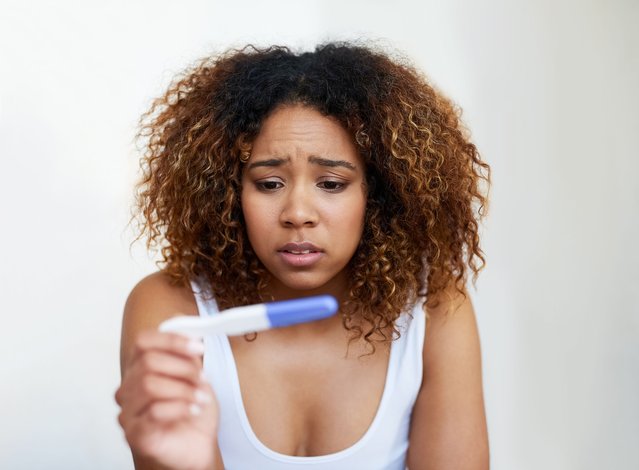 Shot of a young woman looking at the results on her pregnancy test. (Photo by Peopleimages/Getty Images)