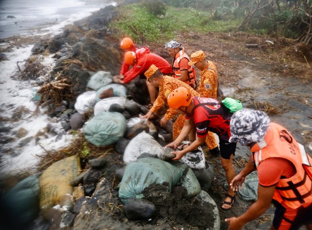 Coastguard personnel rush to repair a damaged storm surge barrier in the coastal town of Buguey, Cagayan province, Philippines, 07 November 2024. According to the latest forecast from Philippine state weather bureau on 07 November, Yinxing intensifies continuously up to super typhoon strength over the Philippine Sea. Yinxing was spotted 175 kilometers east of Aparri, Cagayan province moving west northwestward slowly, packing maximum sustained winds of 165 kilometers per hour (kph) near the center and gustiness of up to 205 kph. (Photo by Francis R. Malasig/EPA/EFE)