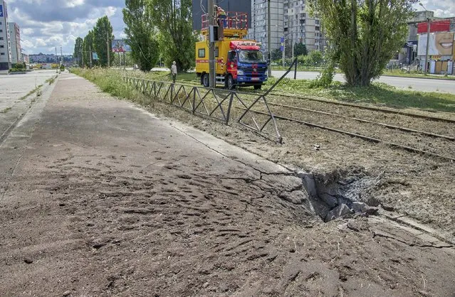 A crater in the road following a Russian rocket strike in Kharkiv, Ukraine, 20 July 2022. At least three people were killed, including a 13-year-old, and two injured in the attack, according to the State Emergency Service. Kharkiv and surrounding areas have been the target of heavy shelling since February 2022, when Russian troops entered Ukraine starting a conflict that has provoked destruction and a humanitarian crisis. (Photo by Sergey Kozlov/EPA/EFE)