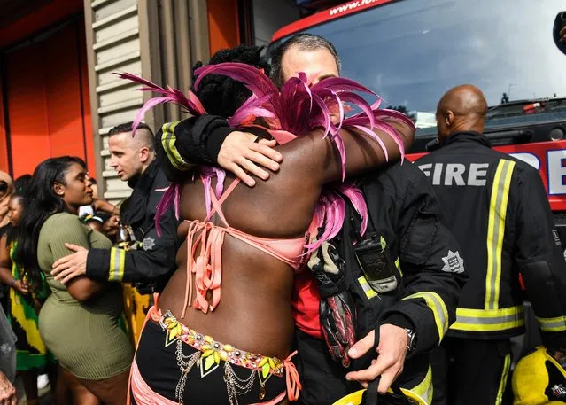 A samba dancer hugs a firefighter following a minute's silence in memory of those killed in the Grenfell Tower blaze at Notting Hill Carnival on August 28, 2017 in London, England. (Photo by Pete Summers/Rex Features/Shutterstock)