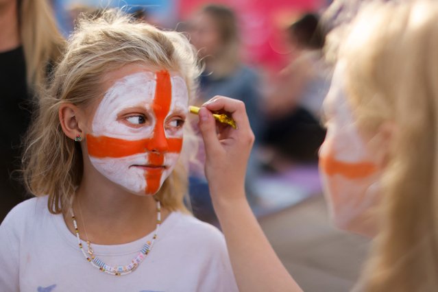 Two England's supporters paint their face with the England's flag as they arrive on the fan zone in Trafalgar Square in front of the National Gallery in London, to attend the UEFA Women's Euro 2022 semi-final football match between England and Sweden at the Bramall Lane stadium, in Sheffield, on July 26, 2022. (Photo by Carlos Jasso/AFP Photo)