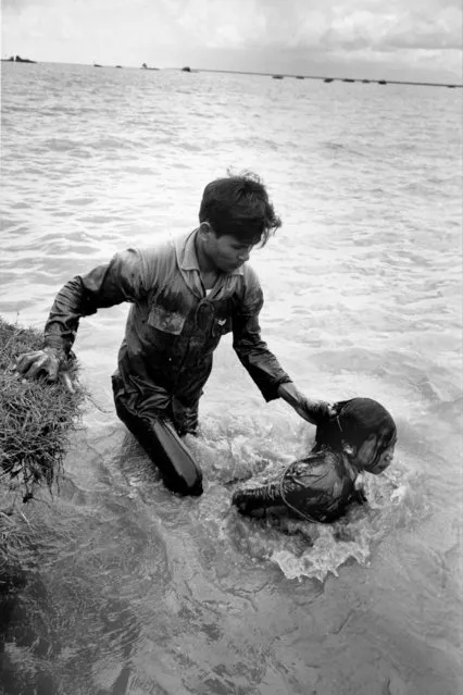 A Vietnamese soldier drags a woman by her hair through a canal in Ap La Ghi, Mekong Delta, August 26, 1965 during the Vietnam War. The woman, suspected of being a Viet Cong collaborator, had her hands tied and was submerged repeatedly as soldiers interrogated her for information about the identity and location of local guerrilla forces.  She was later imprisoned. (Photo by Huynh Thanh My/AP Photo)