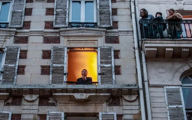 French tenor singer Stephane Senechal (L) sings at his window for the inhabitants of his street in Paris, France, 21 March 2020. Senechal signs every evening since the beginning of containment measures decided by the government to lockdown France in an attempt to stop the widespread of the SARS-CoV-2 coronavirus causing the Covid-19 disease. (Photo by Christophe Petit Tesson/EPA/EFE)