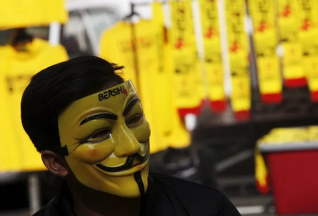 A shopkeeper wearing a pro-democracy group “Bersih” (Clean) mask tends a stall at the Kuala Lumpur and Selangor Chinese Assembly Hall in Malaysia's capital city of Kuala Lumpur August 29, 2015. (Photo by Edgar Su/Reuters)