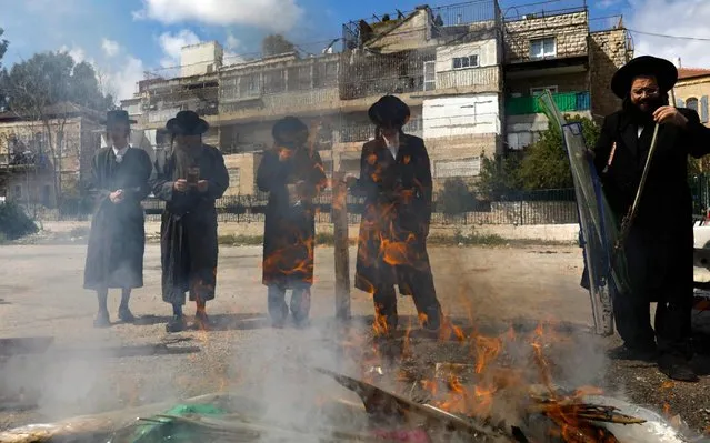 Ultra-Orthodox Jewish men burn food with leavening agents during the Biur Chametz ritual, on April 8, 2020, in the the Ultra-Orthodox Mea Shearim neighbourhood of Jerusalem, ahead of the Jewish Pesach (Passover) holiday, which begins at sunset today. Pesach commemorates the Israelites' exodus from slavery in Egypt some 3,500 years ago and their plight by refraining from eating leavened food products. This year the holiday will be celebrated under lockdown due to measures to curb the spread of COVID-19. (Photo by Menahem Kahana/AFP Photo)