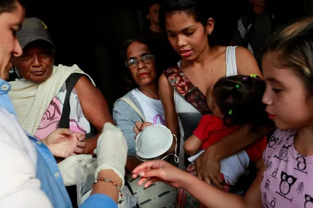 A member of the Taiwan and Venezuela Parliamentary Friendship team hands out free face masks to people outside the metro in Caracas, Venezuela March 12, 2020. (Photo by Carlos Jasso/Reuters)