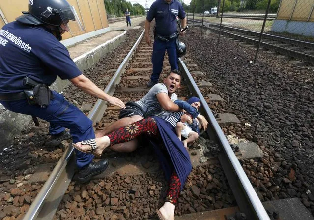 Hungarian policemen stand by the family of migrants protesting on the tracks at the railway station in the town of Bicske, Hungary, September 3, 2015. (Photo by Laszlo Balogh/Reuters)