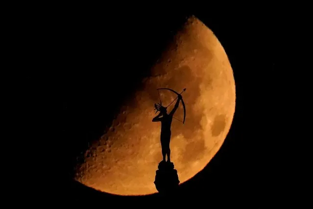 A statue of a Kansa warrior titled “Ad Astra”, atop the Kansas Statehouse is silhouetted against the setting moon Sunday, September 4, 2022, in Topeka, Kan. (Photo by Charlie Riedel/AP Photo)