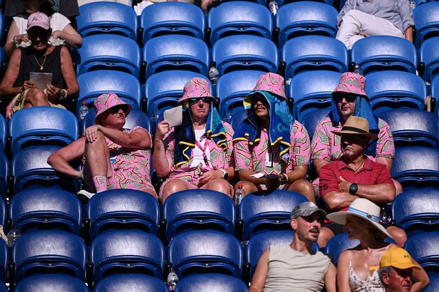 Spectators cover their head from the heat as they watch the men's singles quarterfinal match between USA's Tommy Paul and Germany's Alexander Zverev on day ten of the Australian Open tennis tournament in Melbourne on January 21, 2025. (Photo by William West/AFP Photo)