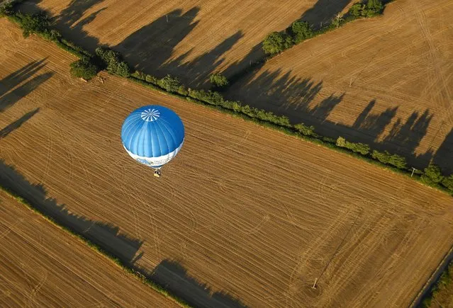 A balloon flies above dry fields during a second heatwave in parts of the country, at the annual Bristol International Balloon Fiesta, in Bristol, Britain on August 12, 2022. (Photo by Toby Melville/Reuters)