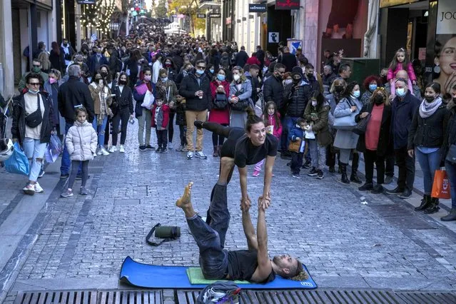 Street artists perform on Ermou Street, Athens' main shopping area, on Friday, December 24, 2021. Christmas concerts and other events have been canceled in Greece as part of new restrictions that include a mask mandate for outdoors and all public areas. (Photo by Thanassis Stavrakis/AP Photo)