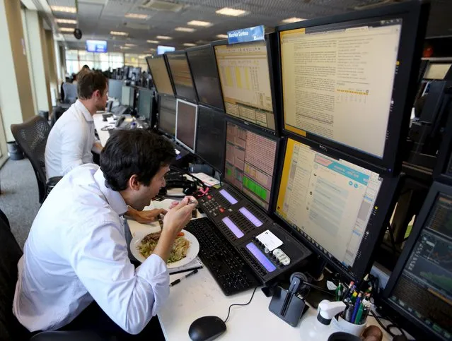 A trader eats lunch at his desk at a brokerage in Sao Paulo, Brazil, September 10, 2015. Brazil's financial markets fell on Thursday after Standard & Poor's cut the country's sovereign rating to junk late Wednesday, though assets began to pare losses in late morning trading as the downgrade had been largely priced in. (Photo by Paulo Whitaker/Reuters)