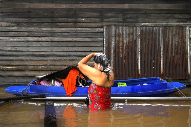 A woman takes a bath on a flooded road after heavy rainfall near Tha-it mosque in Nonthaburi province outskirt of Bangkok, Thailand on October 4, 2022. (Photo by Chalinee Thirasupa/Reuters)
