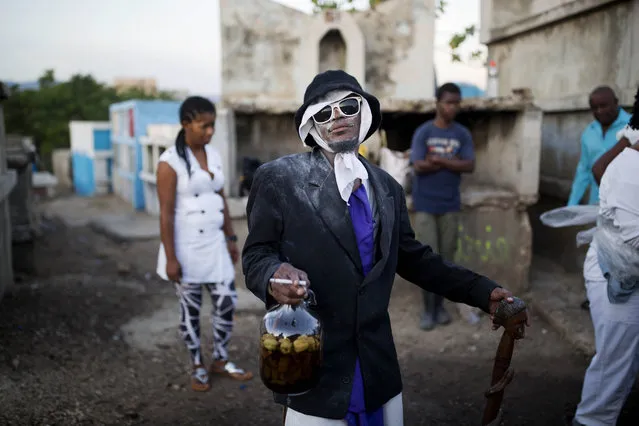 In this November 1, 2017 photo, a man invokes a “Gede” spirit during Haiti's annual Voodoo festival Fete Gede, at the National Cemetery in Port-au-Prince. Revelers stream into cemeteries across the country, in a two-day celebration, to honor Baron Samedi, the guardian of the dead and ruler of the graveyard, and the rest of the Gede spirits which represent death and fertility. (Photo by Dieu Nalio Chery/AP Photo)