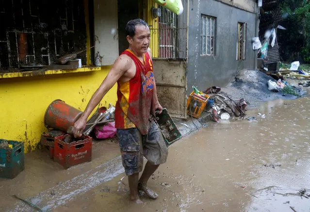 A flood victim retrieves a case of beer from his shop swamped with flood in San Mateo, Rizal, Philippines, August 14, 2016. (Photo by Erik De Castro/Reuters)