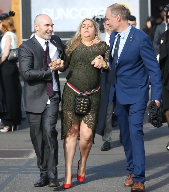 A woman is helped to walk away by two men as her day at the races comes to an end on 2017 Derby Day at Flemington Racecourse on November 4, 2017 in Melbourne, Australia. (Photo by Splash News and Pictures)