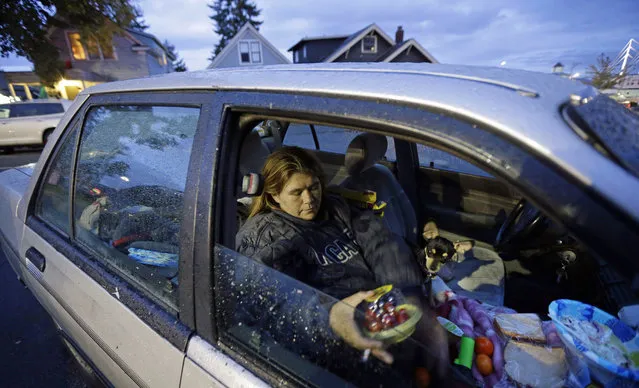 In this October 12, 2017 photo, Paige Clem sits in the car she lives in along with her husband and three dogs outside a church where free food was being distributed in Everett, Wash. Clem, who said she has battled drug addiction in the past but was now clean, said having enough money just to run the heat in her car and move it when required, was a daily challenge. (Photo by Ted S. Warren/AP Photo)