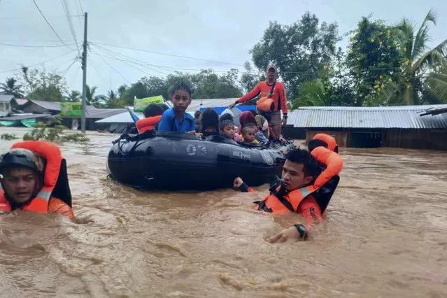 This handout photo taken and released by the Philippine Coast Guard on October 28, 2022 shows rescue workers evacuating people from a flooded area due to heavy rain brought by Tropical Storm Nalgae in Parang, Maguindanao province. Landslides and flooding killed 13 people as heavy rain from approaching tropical storm Nalgae lashed the southern Philippines on October 28, a disaster official said. (Photo by Handout/Philippine Coast Guard (PCG)/AFP Photo)