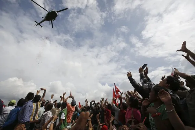 People cheer towards a passing helicopter as they gather during a celebration a day after the first democratic constitution was announced in Kathmandu, Nepal September 21, 2015. (Photo by Navesh Chitrakar/Reuters)