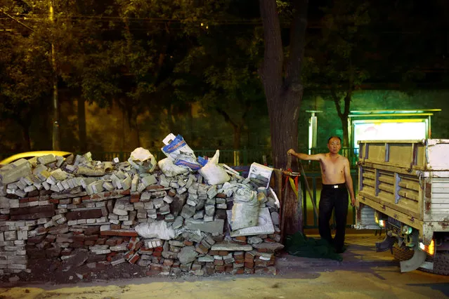 A worker stands next to a pile of bricks at night in Beijing, China, August 25, 2016. (Photo by Thomas Peter/Reuters)