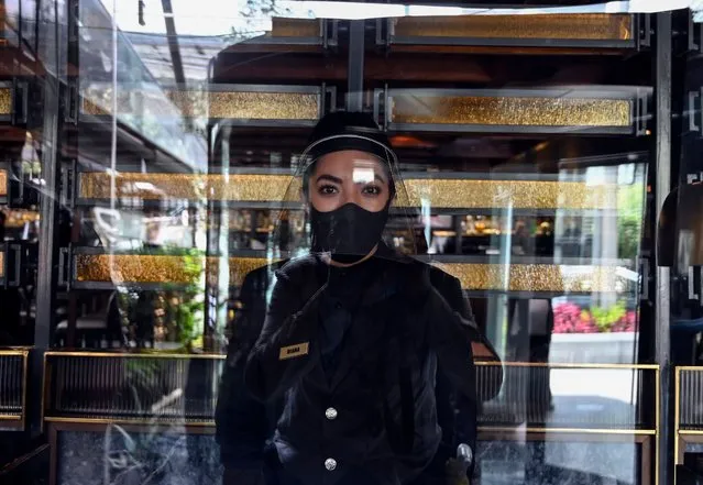 An employee of Cuerno Restaurant, wearing a face mask, waits for customers at the Polanco neighborhood in Mexico City on July 7, 2020 amid the new coronavirus pandemic. Mexico authorised the reopening of restaurants, shops, street markets and sport complexes but with limited capacity and hours amid the COVID-19 novel coronavirus pandemic. (Photo by Alfredo Estrella/AFP Photo)
