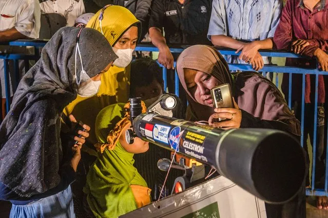 Indonesians use a telescope to watch the lunar eclipse in Surabaya on November 8, 2022. (Photo by Juni Kriswanto/AFP Phoot)