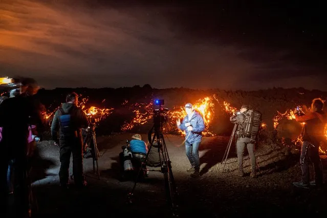 Members of the media report in front of a lava flow during the Mauna Loa volcano eruption in Hawaii, U.S. November 30, 2022. (Photo by Go Nakamura/Reuters)